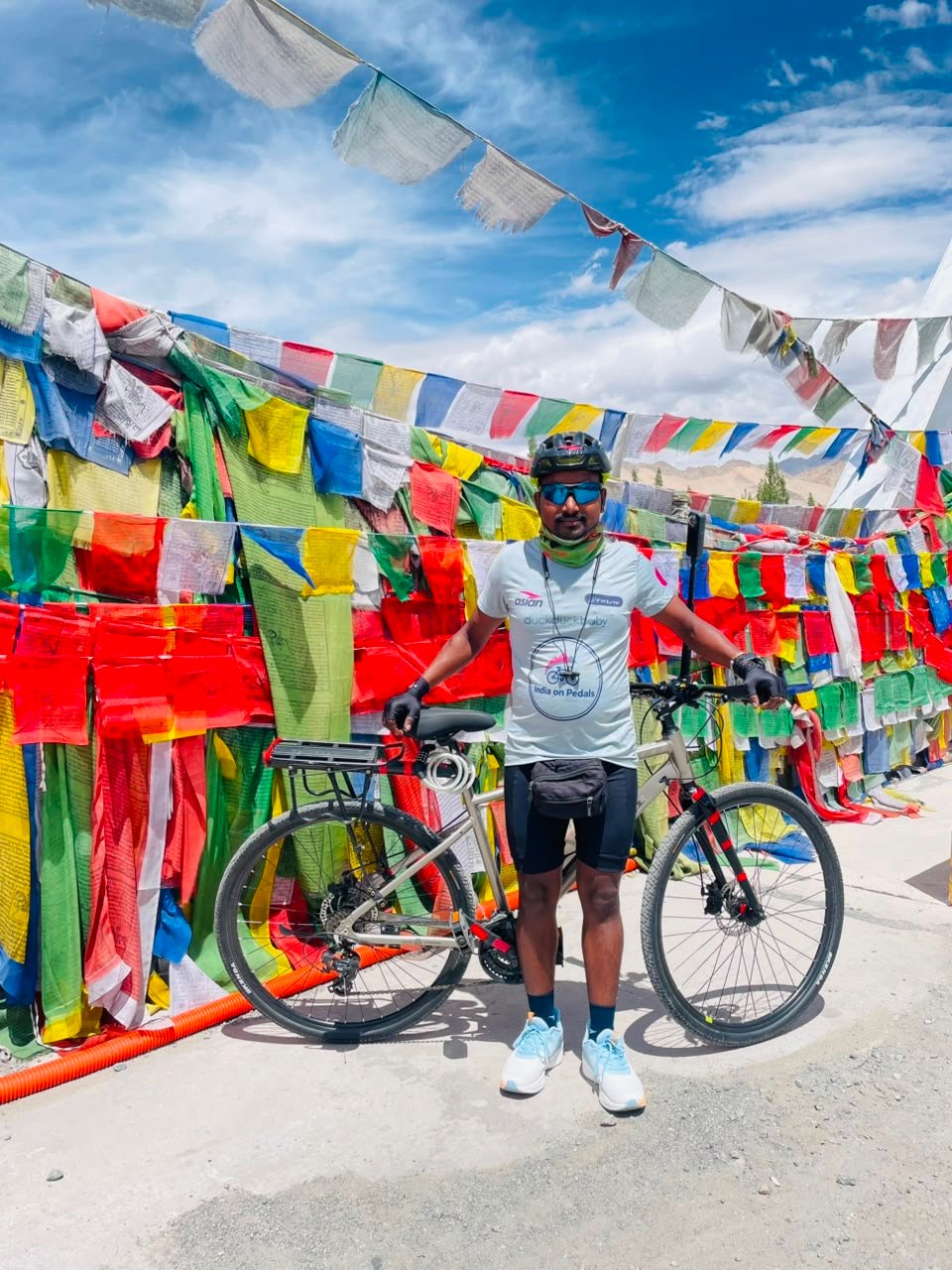 Shankar Kumar Thakur with his bicycle in Leh surrounded by Himalayan prayer flags